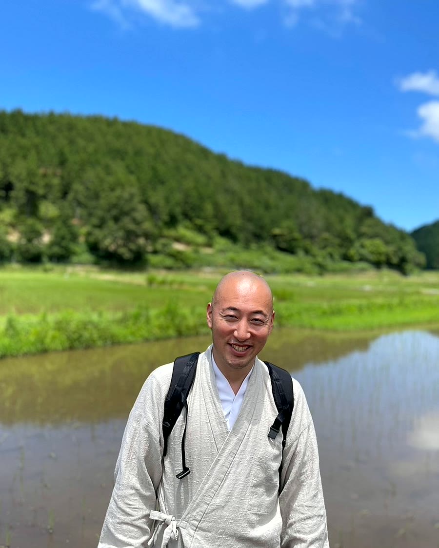田畑に立つ水穂株式会社 代表取締役 大西晶允（清水寺 僧侶）